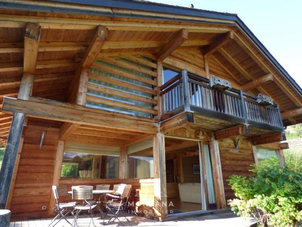 une cabane en rondins avec un balcon, une table et des chaises dans l'établissement Chalet de luxe au calme avec salle de jeux, belle terrasse et proximité ski - Grand-Bornand - FR-1-458-193, au Grand-Bornand