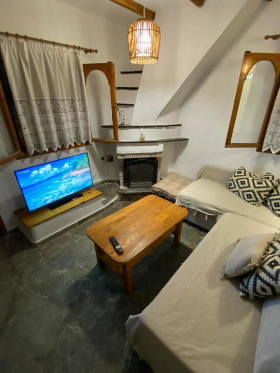 a living room with a couch and a table and a television at Elsa's Poem in Paralia Katerinis