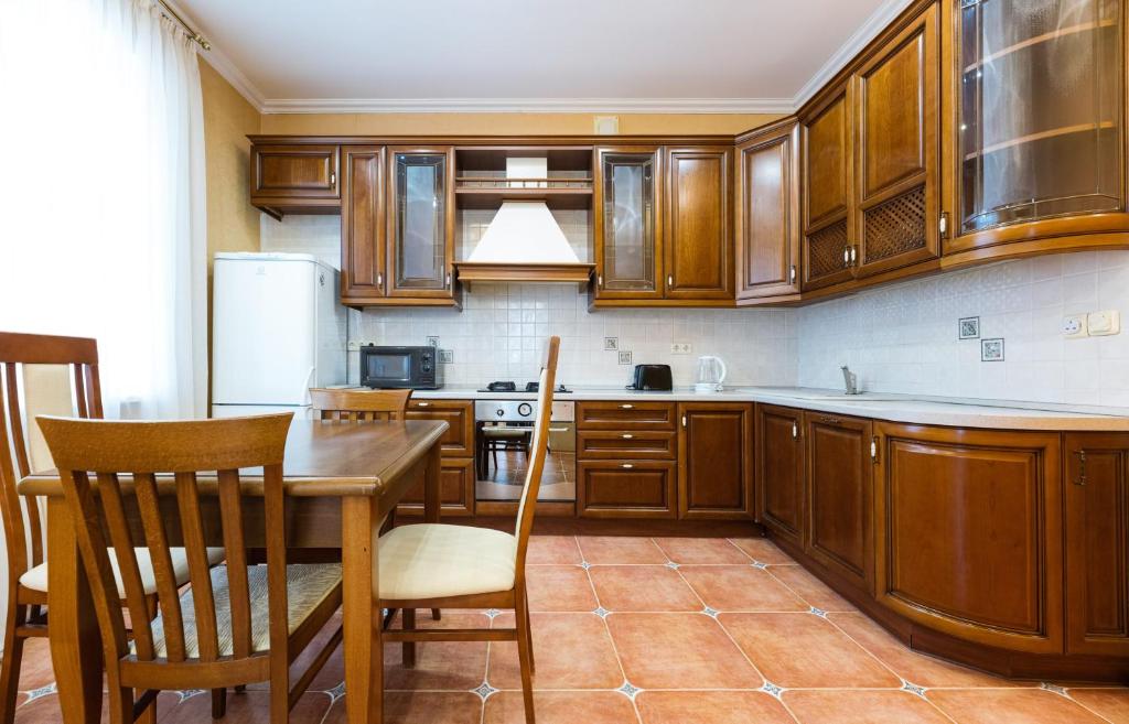 a kitchen with wooden cabinets and a table and chairs at Kyiv Sheikh's Apartment in Kyiv