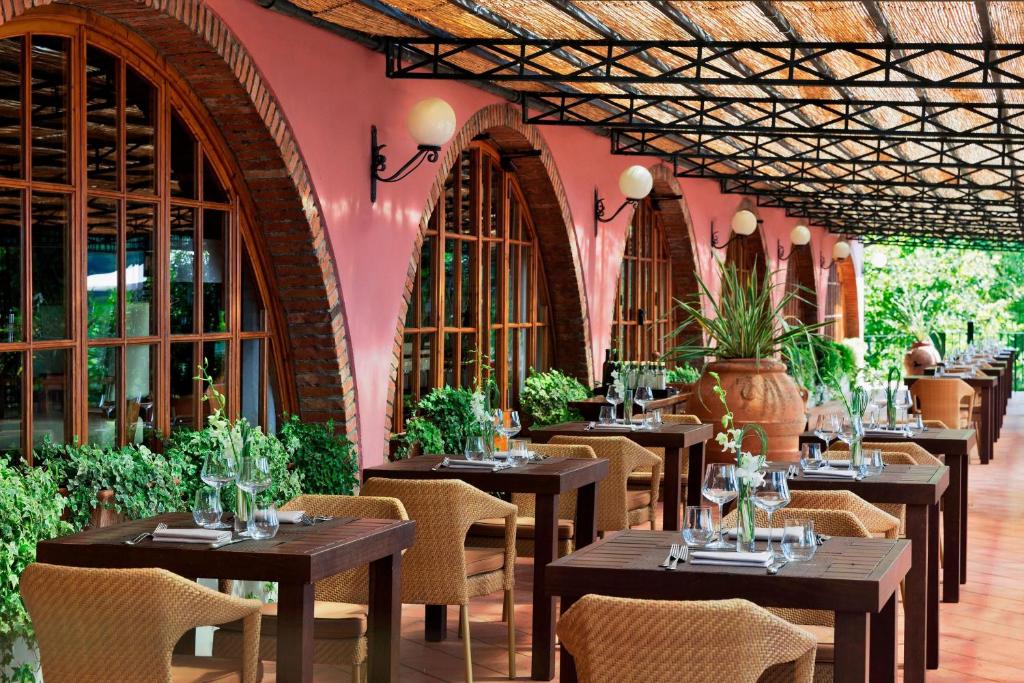 restauracja ze stołami i krzesłami oraz różową ścianą w obiekcie Renaissance Tuscany Il Ciocco Resort & Spa w mieście Barga