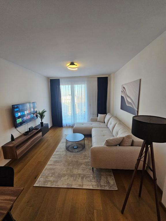 a living room with a couch and a tv at Skyline Cozy Suites in Novi Sad