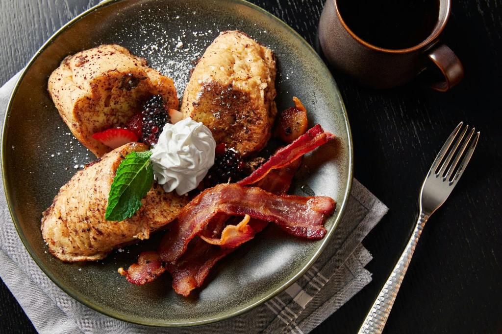 a plate of breakfast food with bacon and french toast at Renaissance Mobile Riverview Plaza Hotel in Mobile