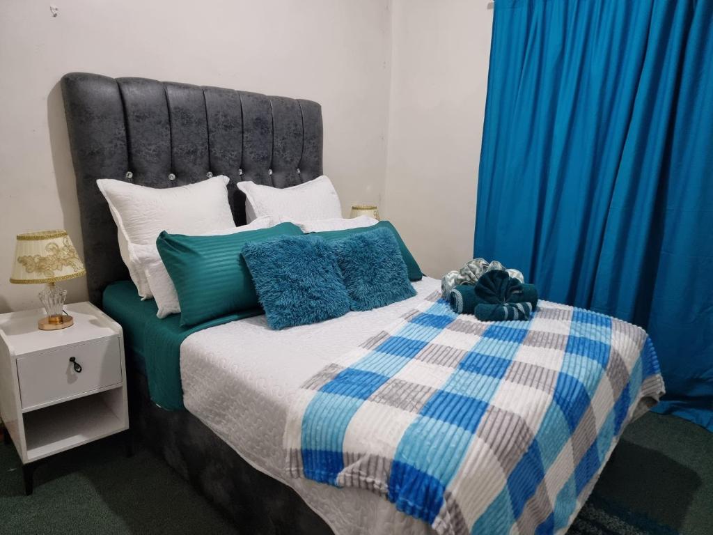 Una cama con una manta azul y blanca y almohadas. en The Leafy Haven, en Harare