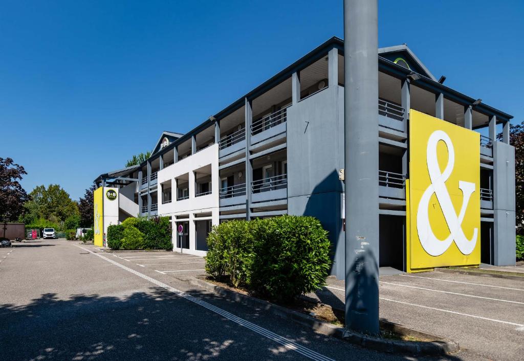un bâtiment avec un panneau jaune et blanc sur celui-ci dans l'établissement B&B HOTEL Grenoble Université 1, à Gières