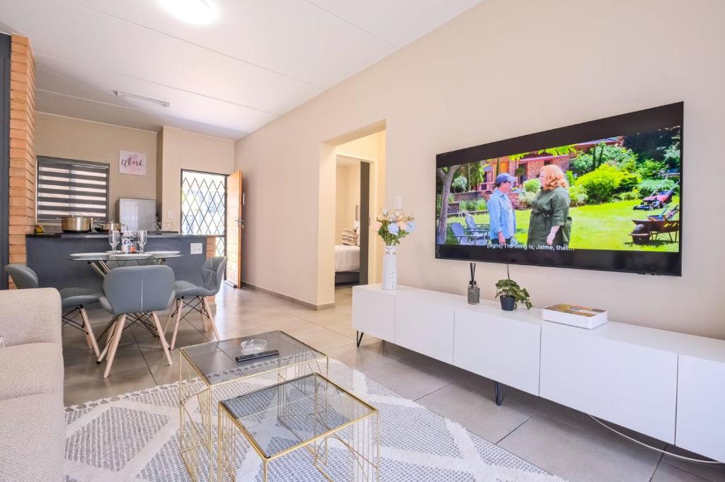 a living room with a large flat screen tv on the wall at Ridge Comfort in Midrand