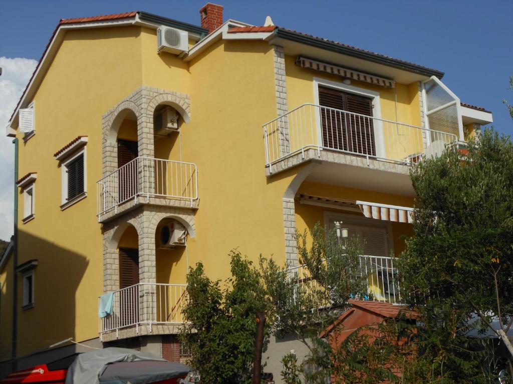 拉布的住宿－Apartments Casa Barbara，黄色的房子,设有白色的阳台和树木