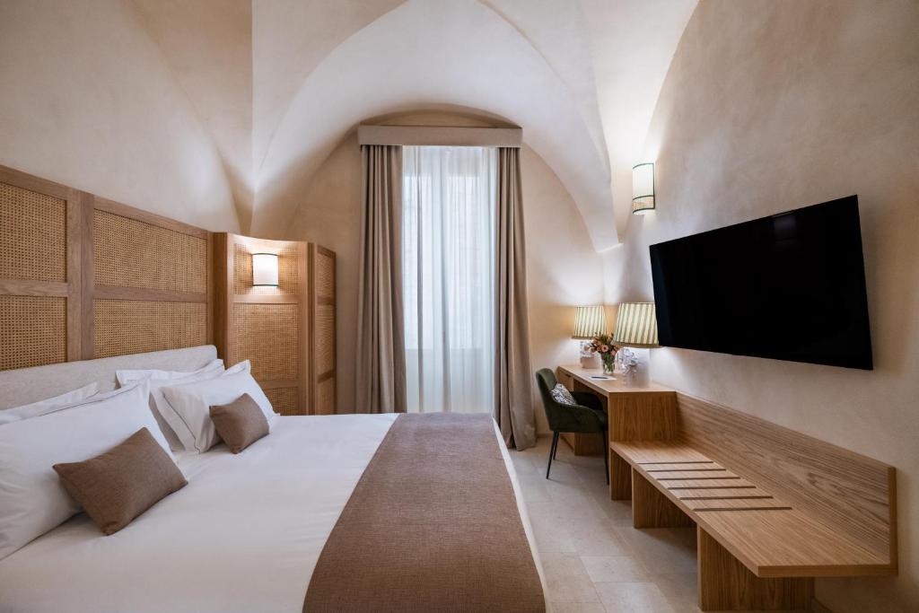 レッチェにあるPalazzo Paisiello - Luxury Rooms Lecceのベッドルーム1室(大型ベッド1台、壁掛けテレビ付)