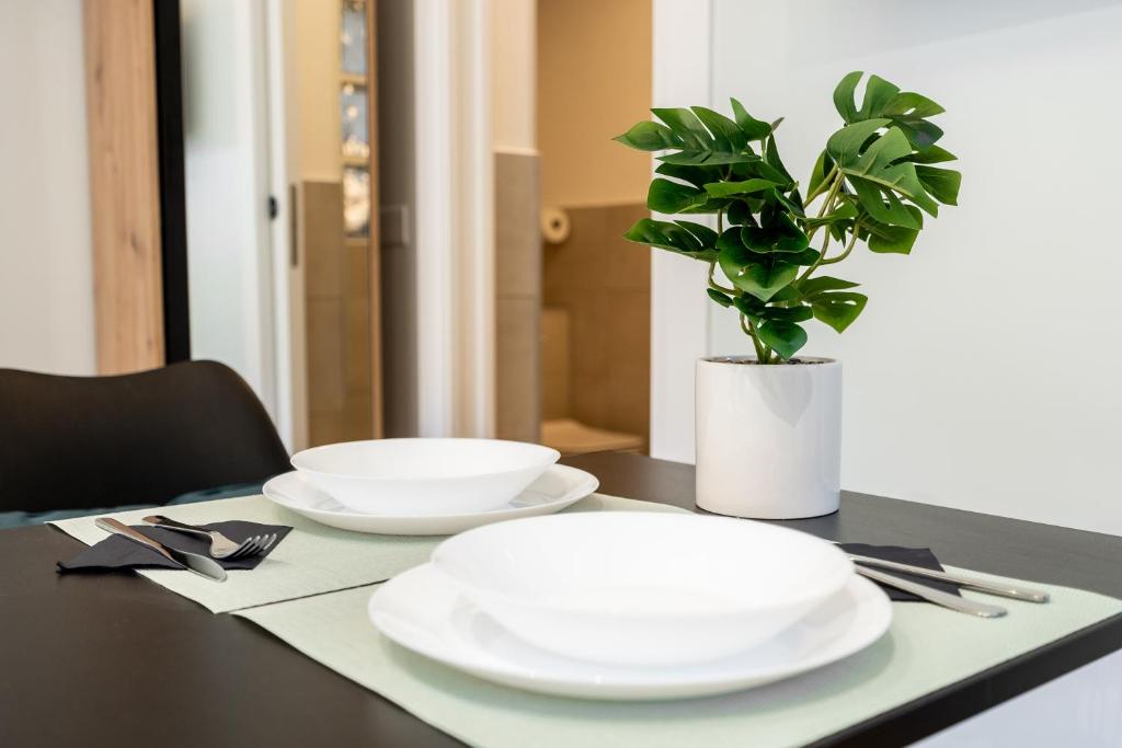 a table with two white plates and a potted plant at Suite Room Suriani in Rome