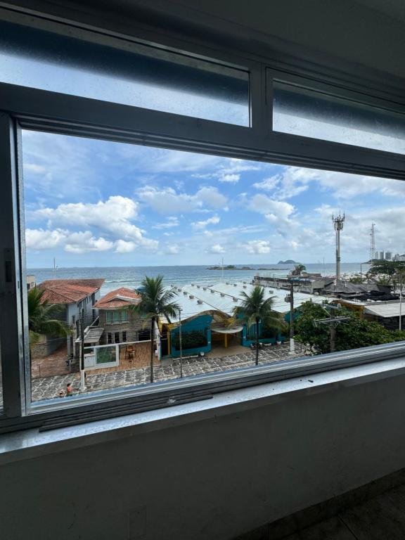a window with a view of the ocean and buildings at Apartamento em frente ao mar in Guarujá