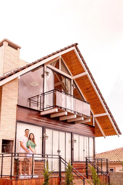 a man and woman standing in front of a house at Chalé Cruzeiro do Sul, hidromassagem, 2 min Thermas Machadinho-RS#3 in Machadinho