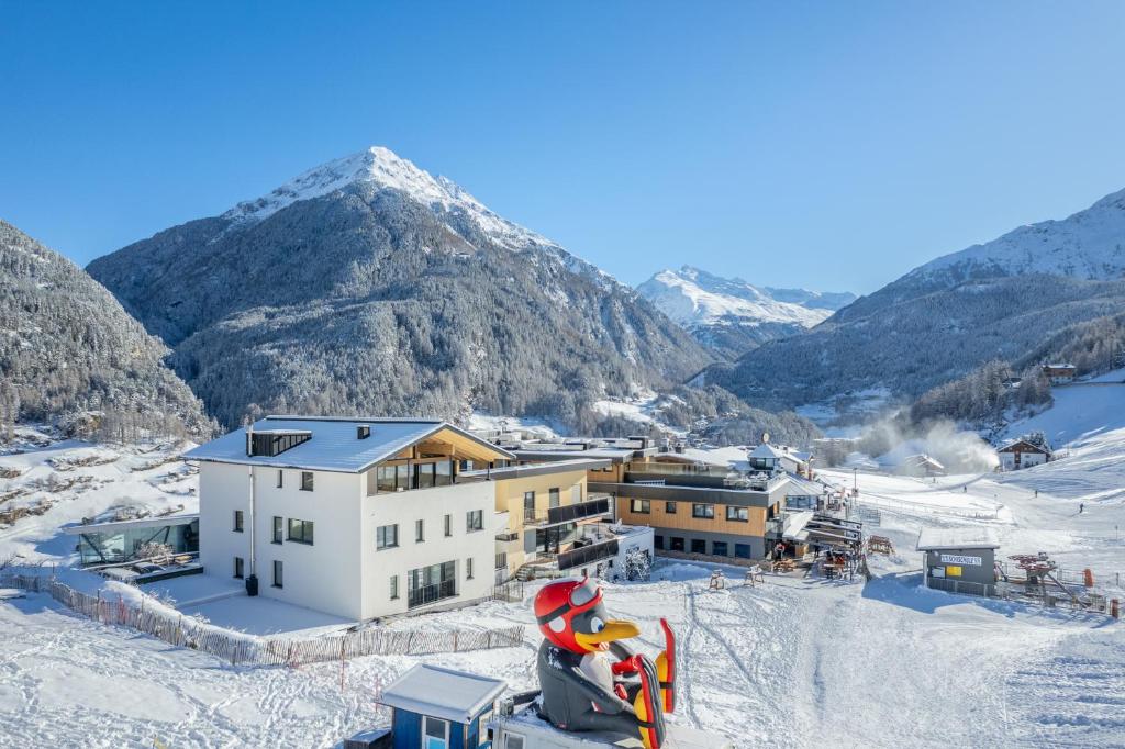 a building in the snow with mountains in the background at Apart Sonnenbichl in Sölden