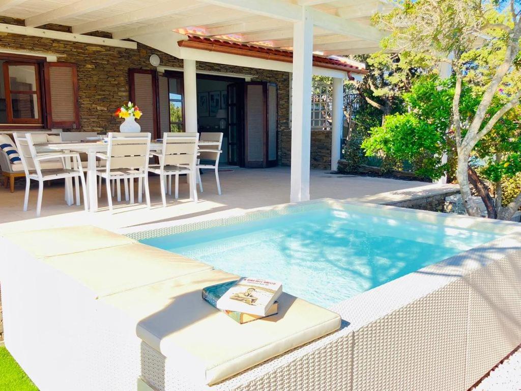 a hot tub on a patio with a table and chairs at Villetta con piscina e ampio giardino in Stintino
