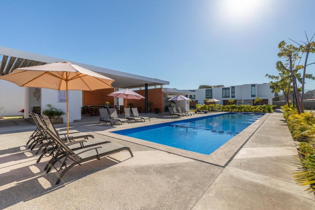 a swimming pool with chairs and an umbrella at Ebano Residential in Las Juntas