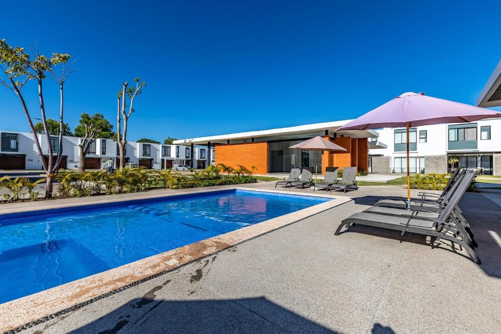 a swimming pool with two chairs and an umbrella at Ebano Residential in Las Juntas