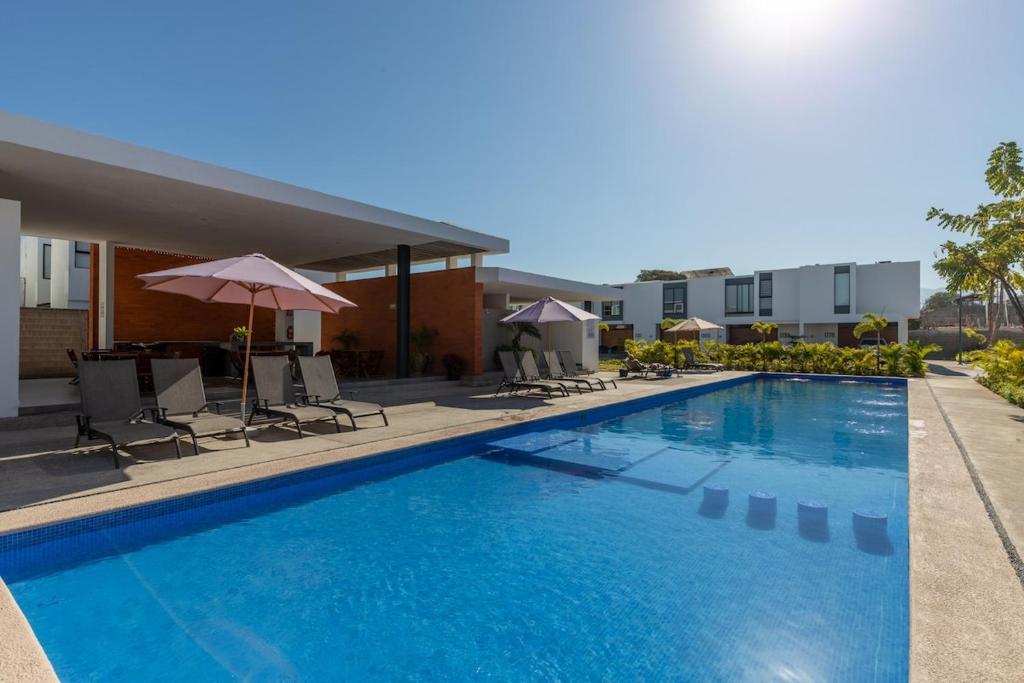 a swimming pool with chairs and umbrellas next to a building at Ebano Residential in Las Juntas