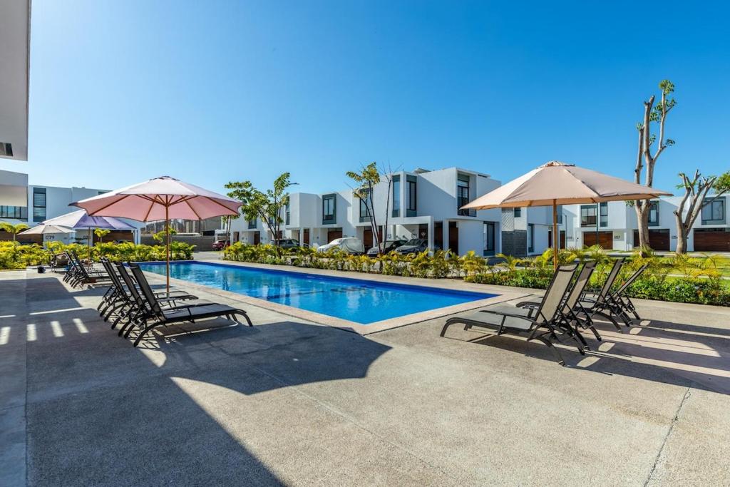 a swimming pool with chairs and umbrellas in front of a building at Ebano Residential in Las Juntas