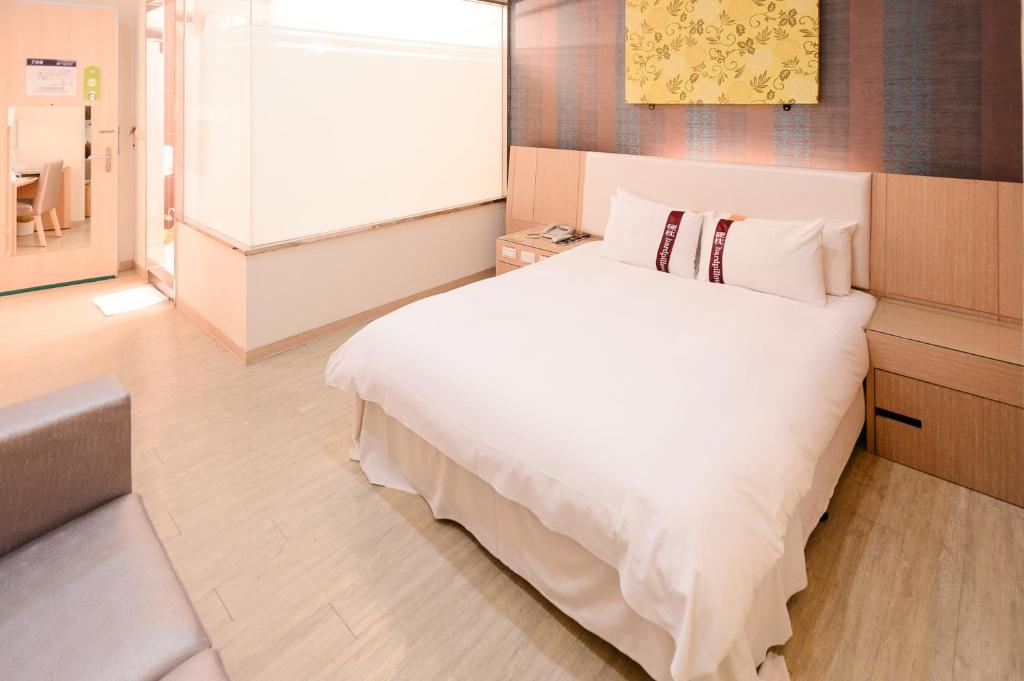 a bedroom with a white bed and a window at i-Deal Hotel in Taichung