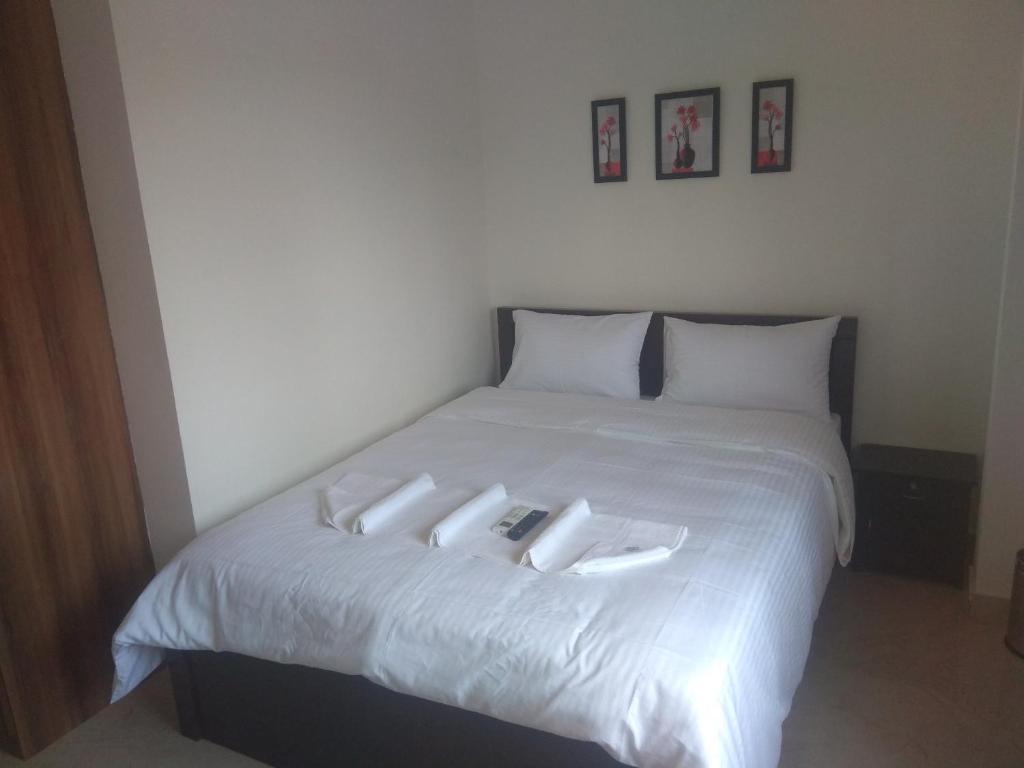 een wit bed met drie witte kussens erop bij Sk Residency in Bangalore