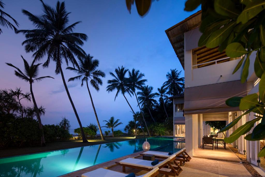 a villa with a swimming pool at night at Sri Villas in Bentota