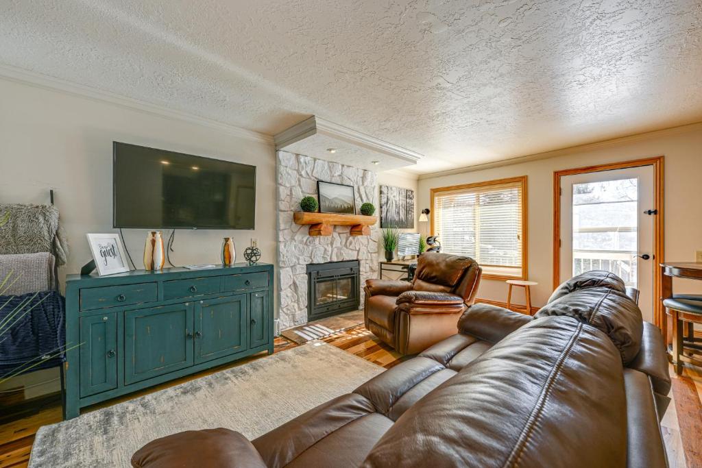 a living room with a leather couch and a television at Walk to Giant Steps Mtn Retreat with Hot Tub Access in Brian Head