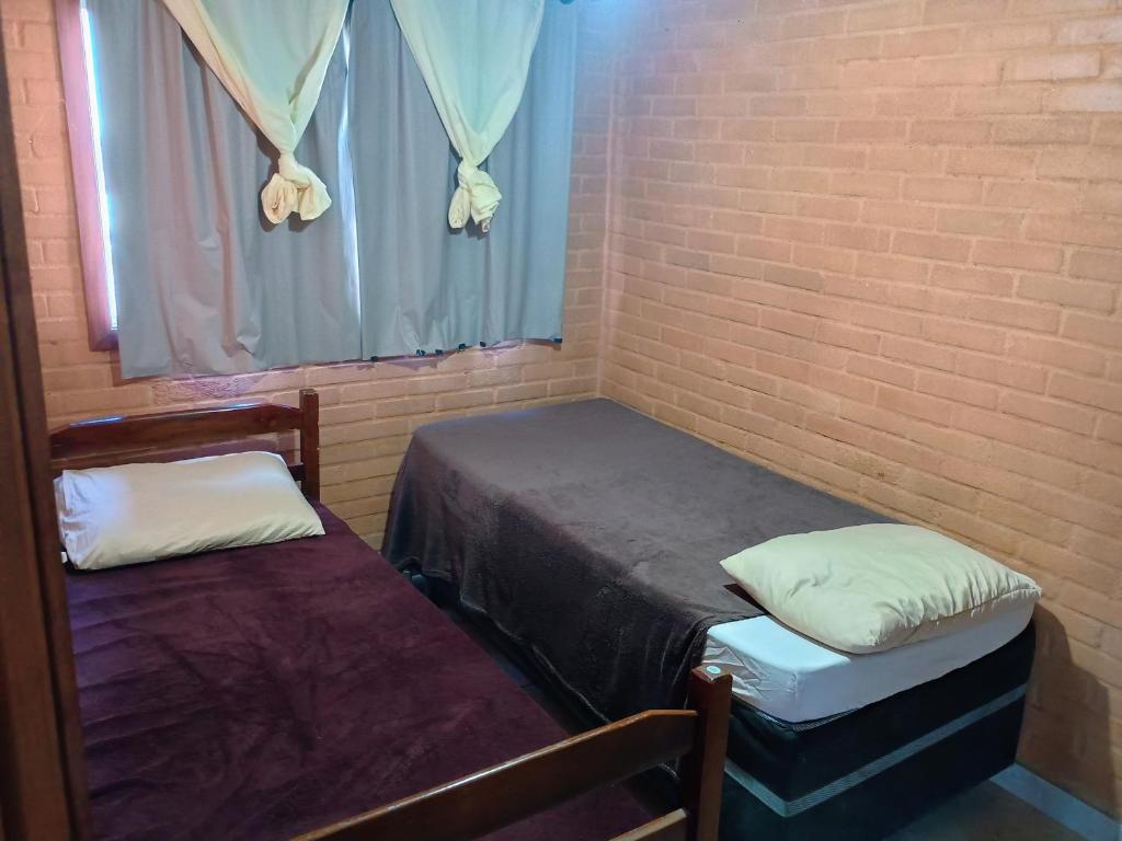 two beds in a room with a brick wall at Flat de 2 quartos com AR na área central de GV com conzinha completa-garagem-wifi-Bom p grupos ou familias ou empresas in Governador Valadares