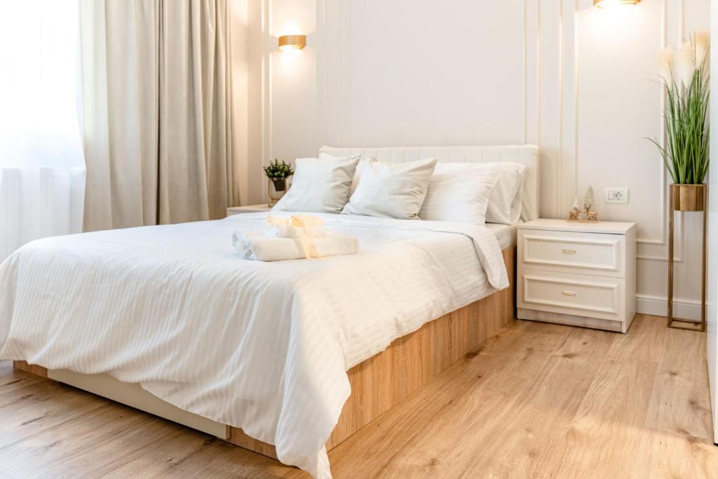 a white bedroom with a large bed with white sheets at Confort si Elegantă - Elit Rental LRL in Timişoara
