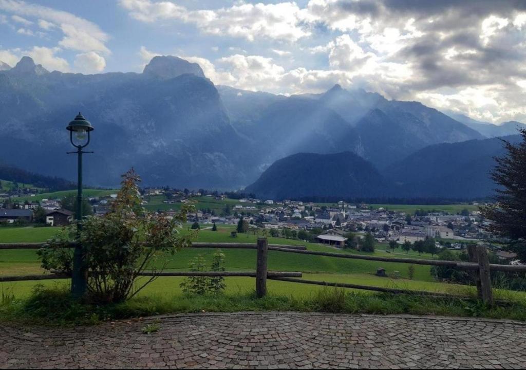 a field with a fence and a town and mountains at Sonnleit'n Zimmer 2 in Abtenau