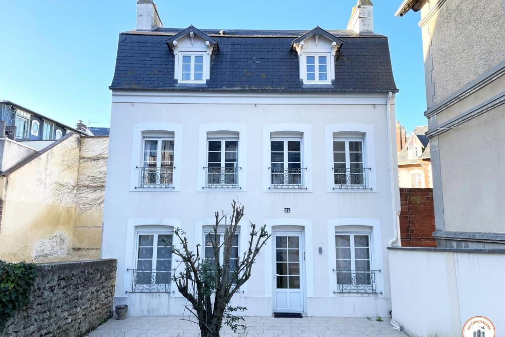 a white house with a black roof at The Garden House - Jardin Parking Hypercentre in Deauville