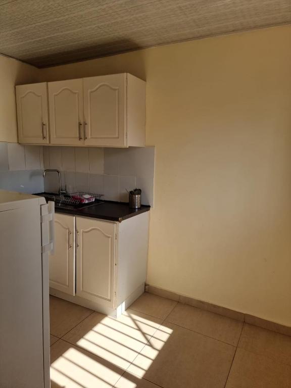 a kitchen with white cabinets and a white refrigerator at Hideout in Highlands in Harare