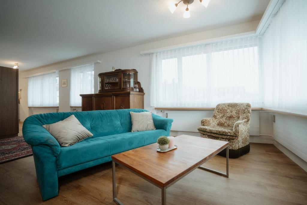 a living room with a blue couch and a chair at Apartment Alpenblick in Amden