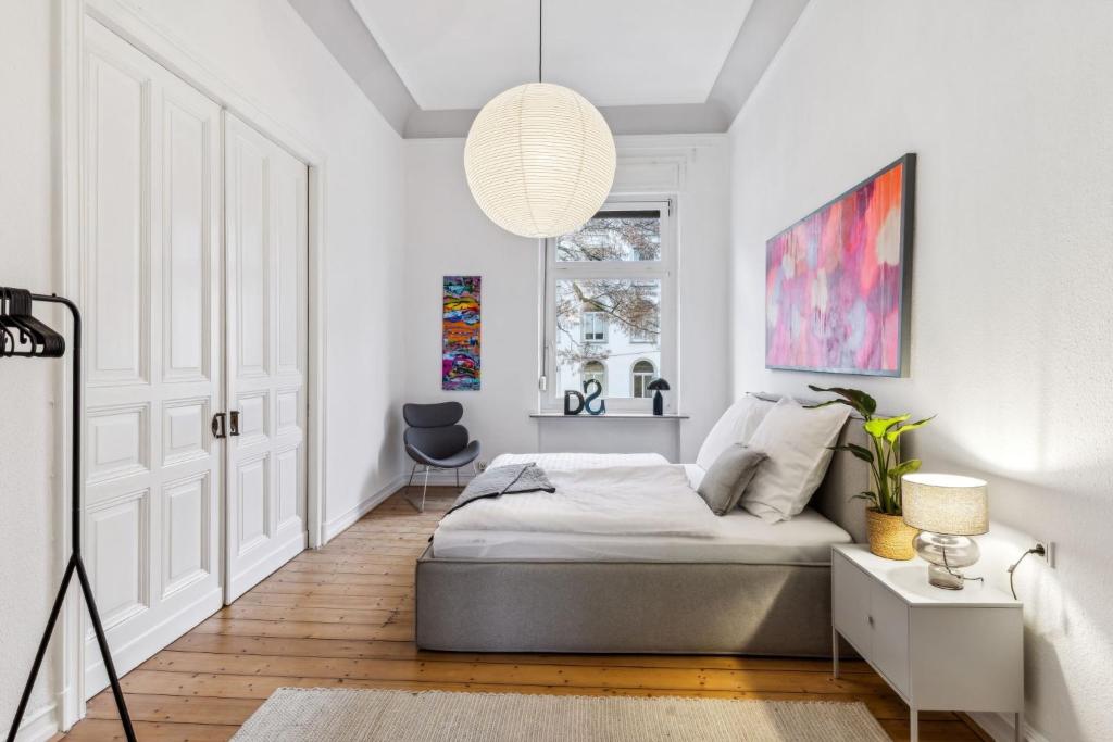 a white bedroom with a bed and a window at Gründerzeit Domizil Altbau Neu in Wuppertal