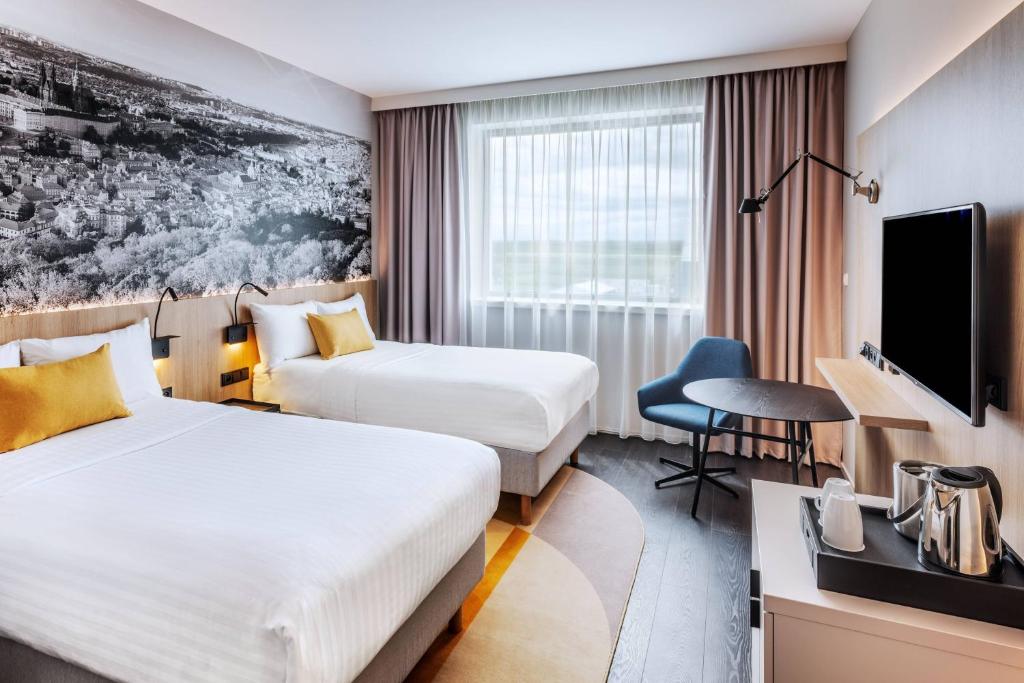a hotel room with two beds and a tv at Courtyard by Marriott Prague Airport in Prague