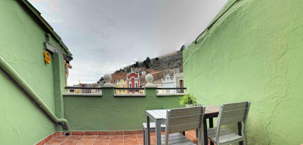 pared verde con mesa y sillas en el balcón en Ático del Holandés, en Balaguer