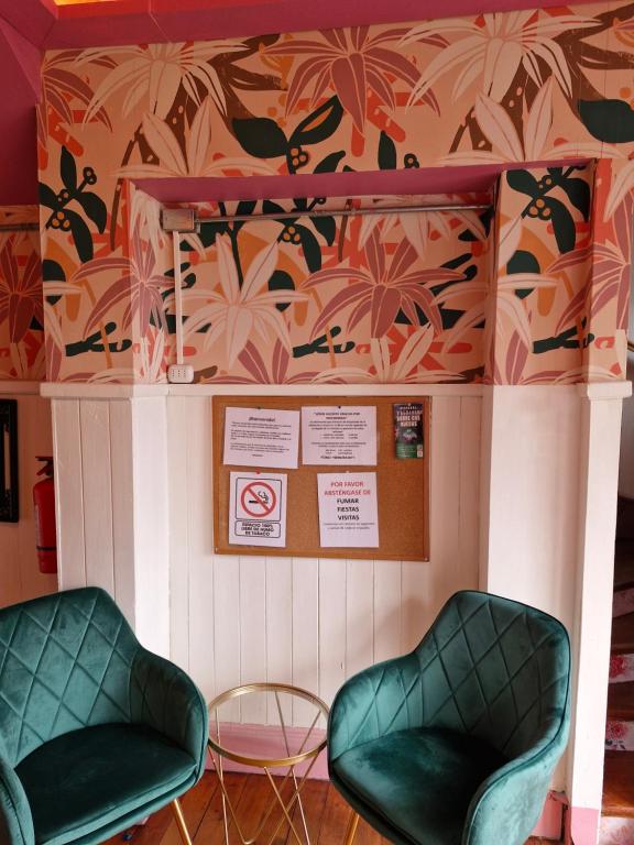 2 sillas verdes en una habitación con papel pintado en Hostal Arrayan, en Valdivia
