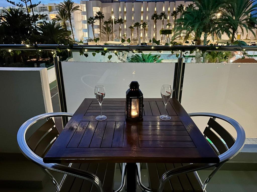 een tafel met wijnglazen en een kaars op een balkon bij Cozy Apartament Maspalomas in San Bartolomé