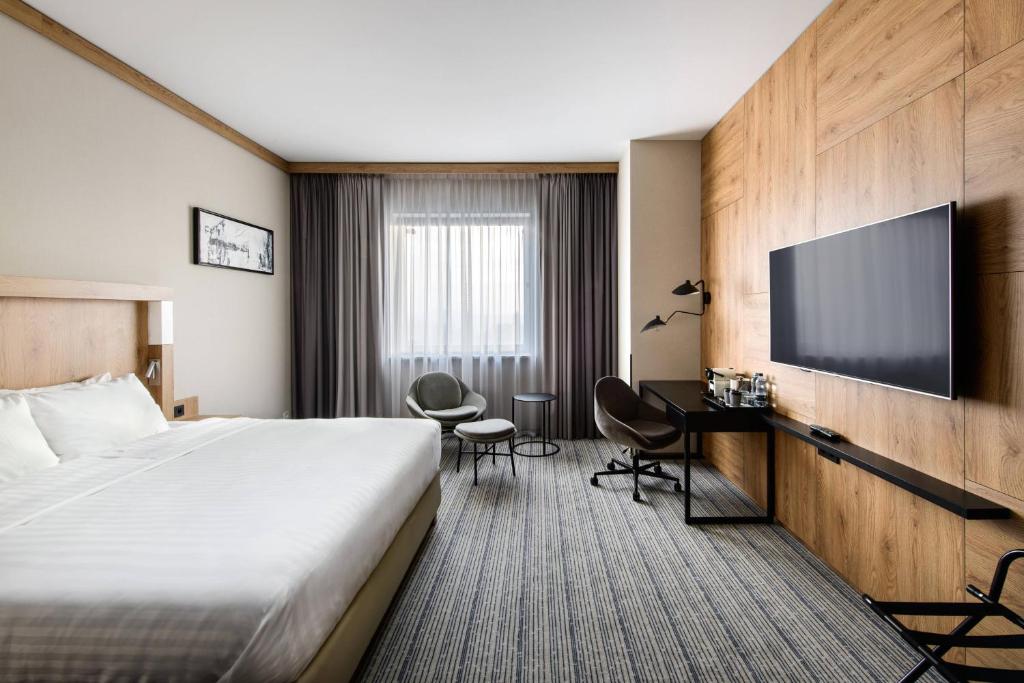 a hotel room with a bed and a flat screen tv at Courtyard by Marriott Warsaw Airport in Warsaw