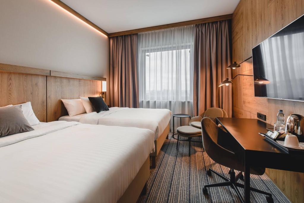 a hotel room with two beds and a desk at Courtyard by Marriott Warsaw Airport in Warsaw