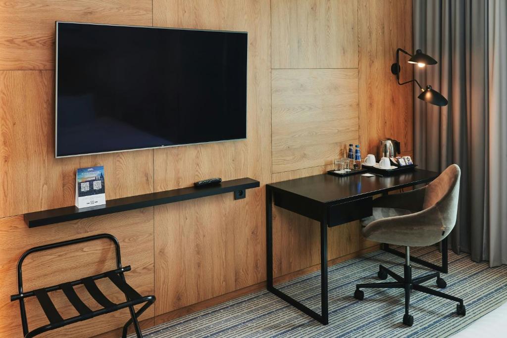 a hotel room with a desk and a television on a wall at Courtyard by Marriott Warsaw Airport in Warsaw