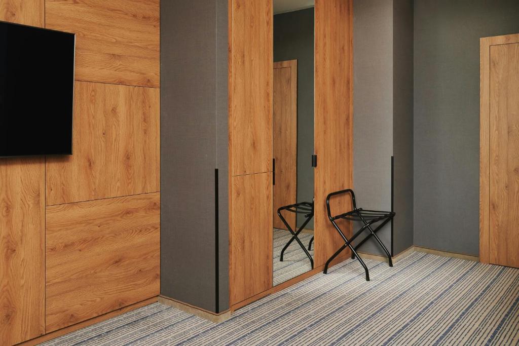 a room with a sliding door with a chair and a television at Courtyard by Marriott Warsaw Airport in Warsaw