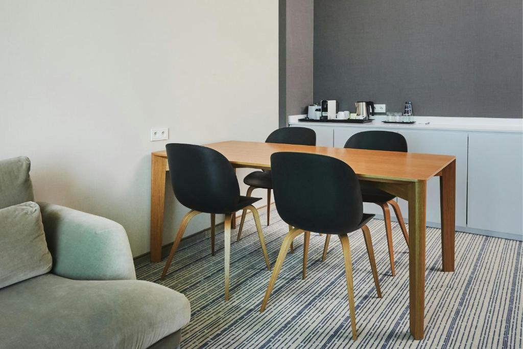 a dining room table with four chairs and a couch at Courtyard by Marriott Warsaw Airport in Warsaw