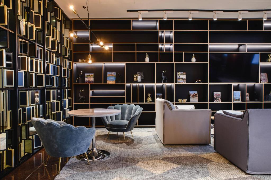 a lobby with chairs and a table and a wall of books at Courtyard by Marriott Warsaw Airport in Warsaw