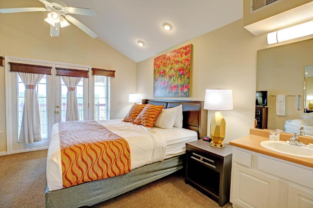 a bedroom with a bed and a bathroom with a sink at Grand Crowne Resort in Branson