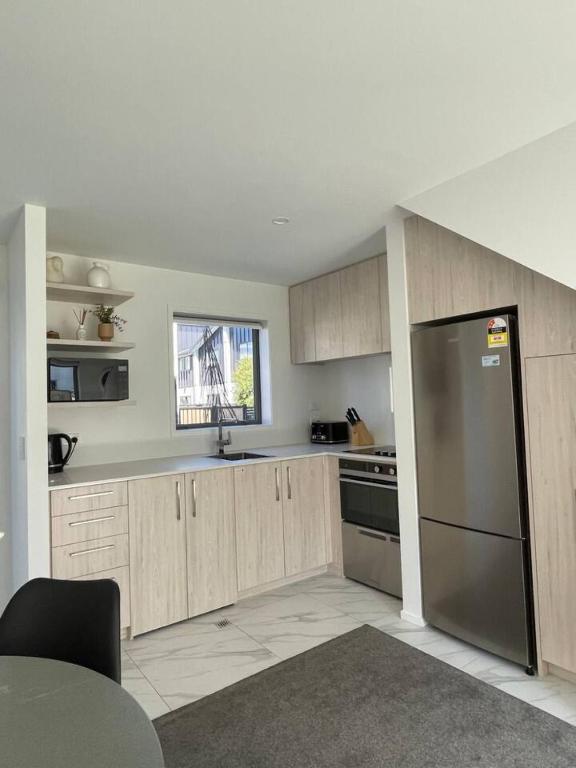 eine Küche mit Holzschränken und einem Edelstahlkühlschrank in der Unterkunft Mohua Lane Retreat in Christchurch