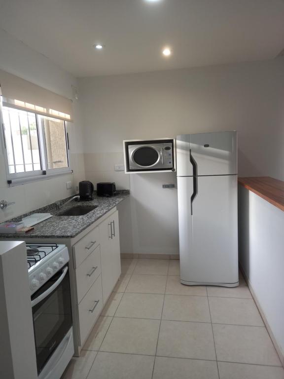 a kitchen with a refrigerator and a microwave at Departamentos Capernaum in Santa Rosa
