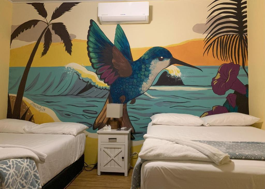 a mural of a bird in a room with two beds at Sunset Hut Hostel in Omoa