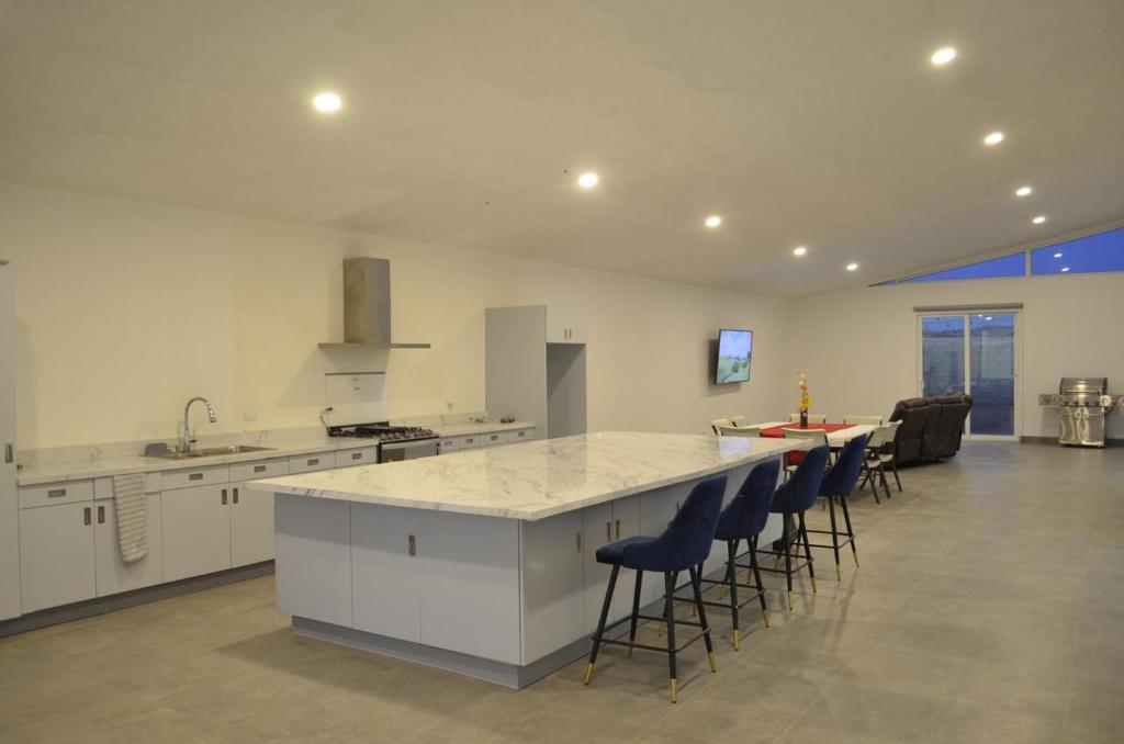 a large kitchen with a counter and chairs in it at CASA LUGO mx in El Porvenir