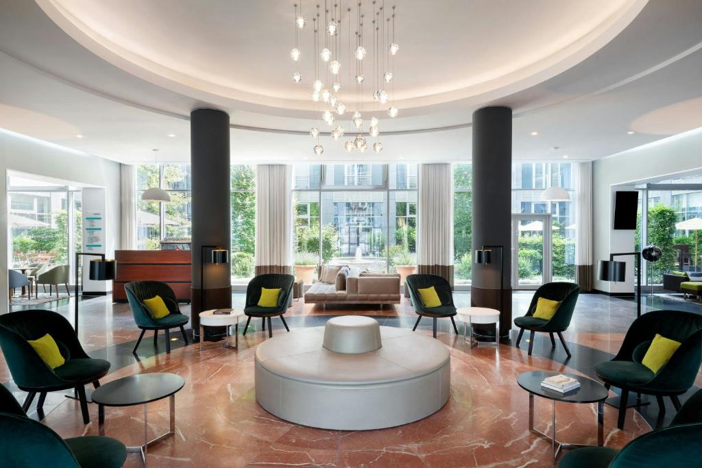 a lobby with chairs and a table and a couch at Le Méridien Munich in Munich