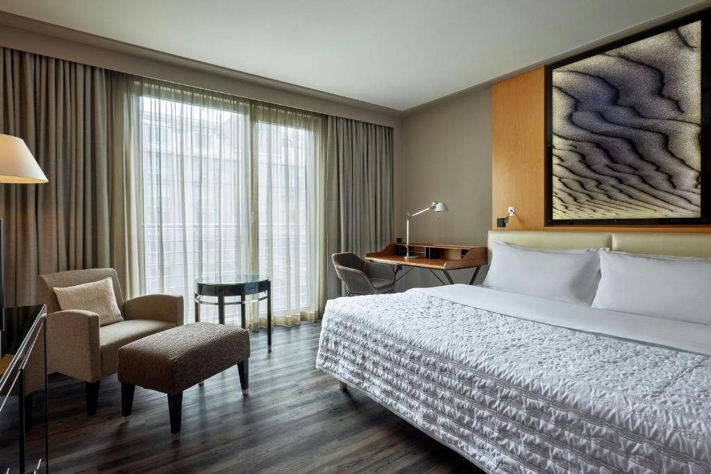 a hotel room with a bed and a desk and chair at Le Méridien Munich in Munich