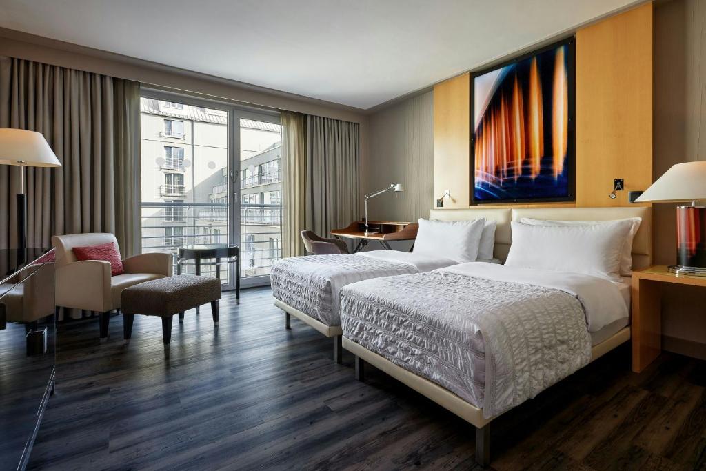 a hotel room with two beds and a desk at Le Méridien Munich in Munich
