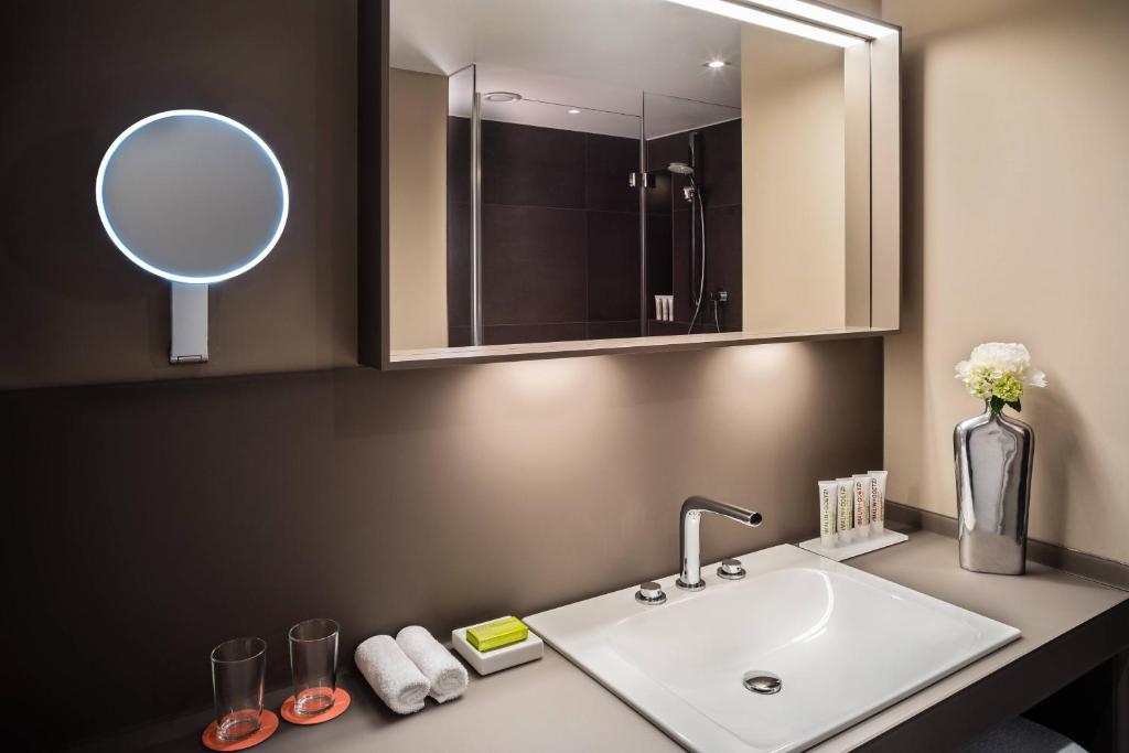 a bathroom with a sink and a mirror at Le Méridien Munich in Munich